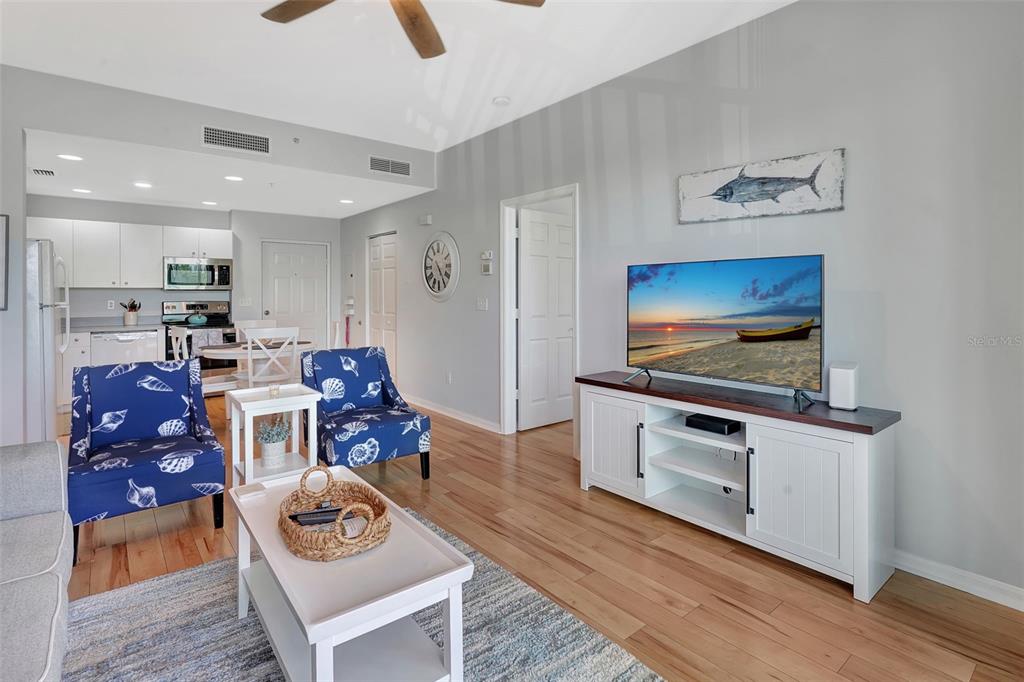 A living room features blue patterned armchairs, a white coffee table, and a television console — 2090 MATECUMBE KEY ROAD UNIT 1207, PUNTA GORDA, FL