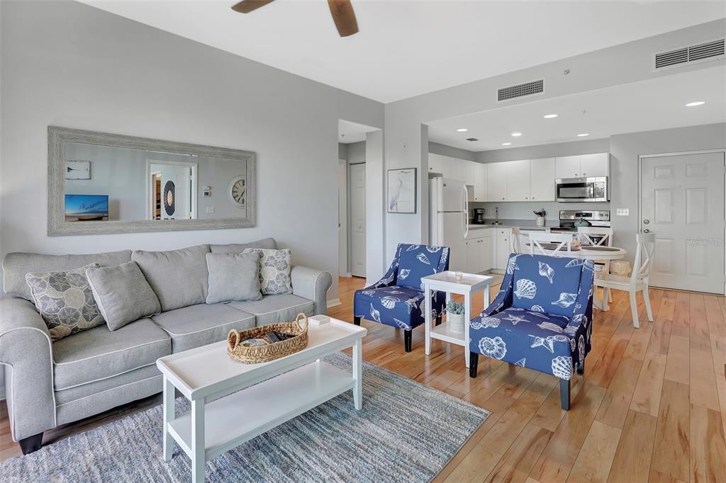 A living room with a gray sofa, two blue patterned chairs, and an open kitchen — 2090 MATECUMBE KEY ROAD UNIT 1207, PUNTA GORDA, FL