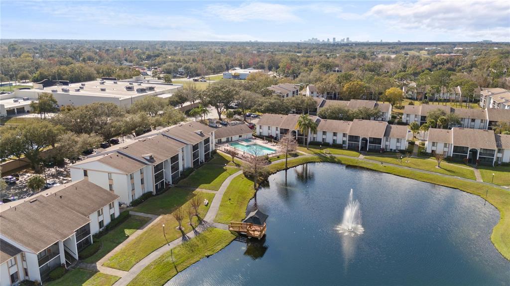 An aerial view shows apartment buildings surrounding a pond with a fountain and a gazebo — 8203 SUN SPRING CIRCLE UNIT 12, ORLANDO, FL