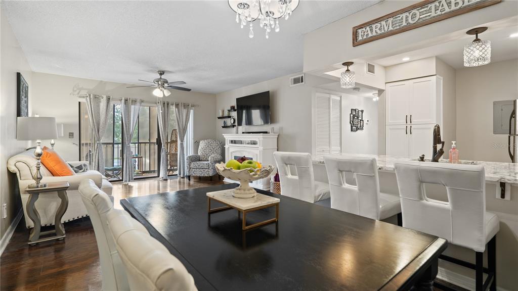 A dining area with a dark table and white chairs opens to a living room — 8203 SUN SPRING CIRCLE UNIT 12, ORLANDO, FL