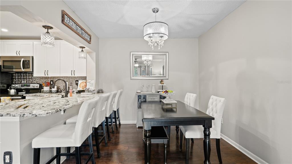 A dining area with a dark table and white chairs sits beside a kitchen island — 8203 SUN SPRING CIRCLE UNIT 12, ORLANDO, FL