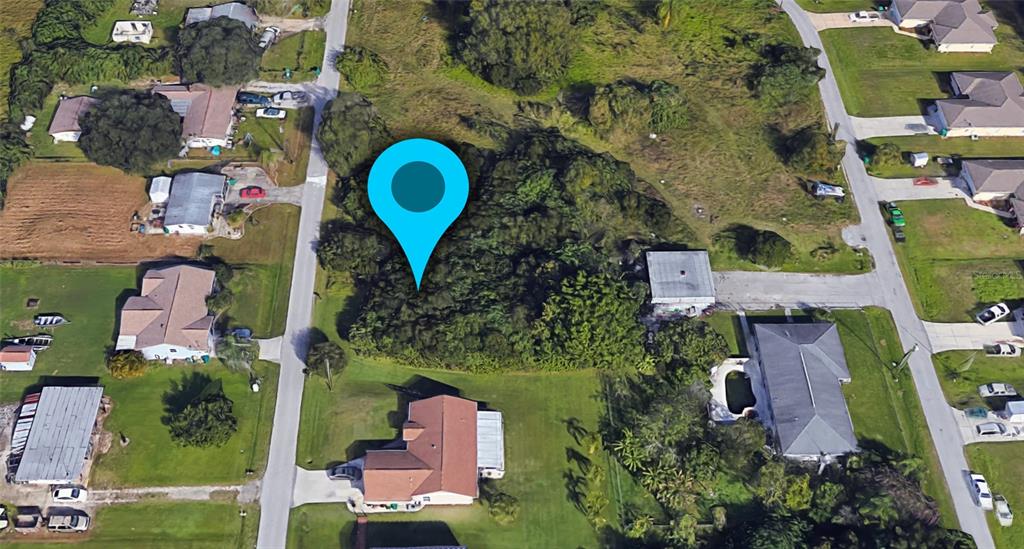 This aerial view shows a wooded, undeveloped residential lot marked by a blue location pin — 1410 PERSAY DRIVE, PUNTA GORDA, FL