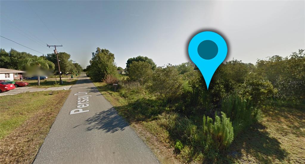 A street view shows a paved road with a vacant, overgrown lot on the right — 1410 PERSAY DRIVE, PUNTA GORDA, FL