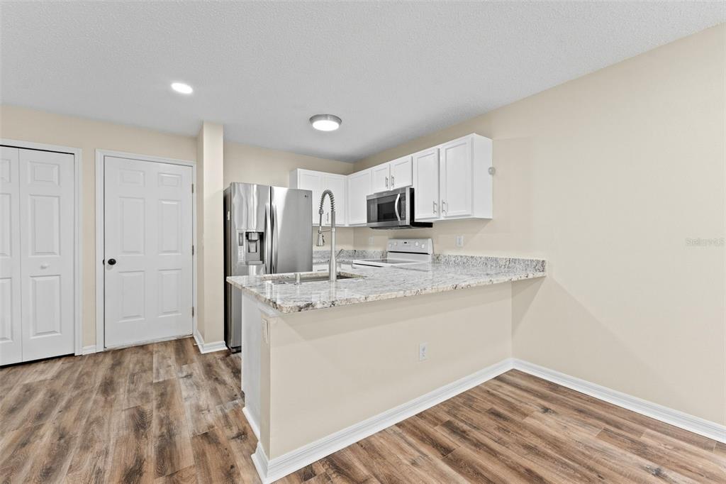 A kitchen featuring white cabinets, granite countertops, stainless steel appliances, and a double-basin sink — 8421 EDGEWATER PLACE BOULEVARD, TAMPA, FL