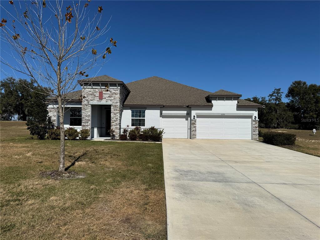 A single-story house with a stone-accented entryway, a three-car garage, and a concrete driveway — 10190 DOLPHIN GULL CIRCLE, THONOTOSASSA, FL