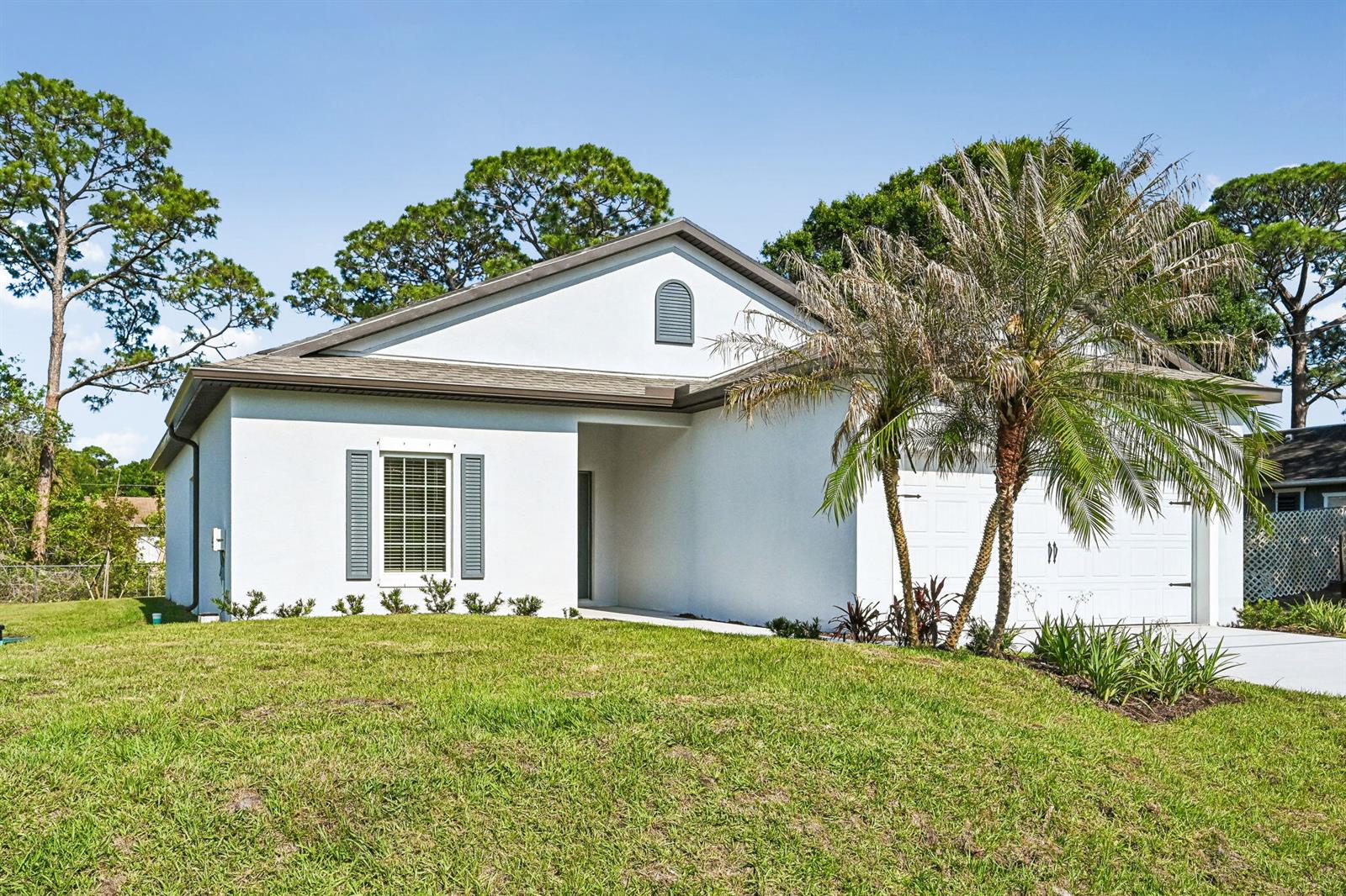 A white, single-story house with a gray roof, a palm tree, and a grassy lawn — 6010 Hickory Drive, Fort Pierce FL 34982, FORT PIERCE, FL