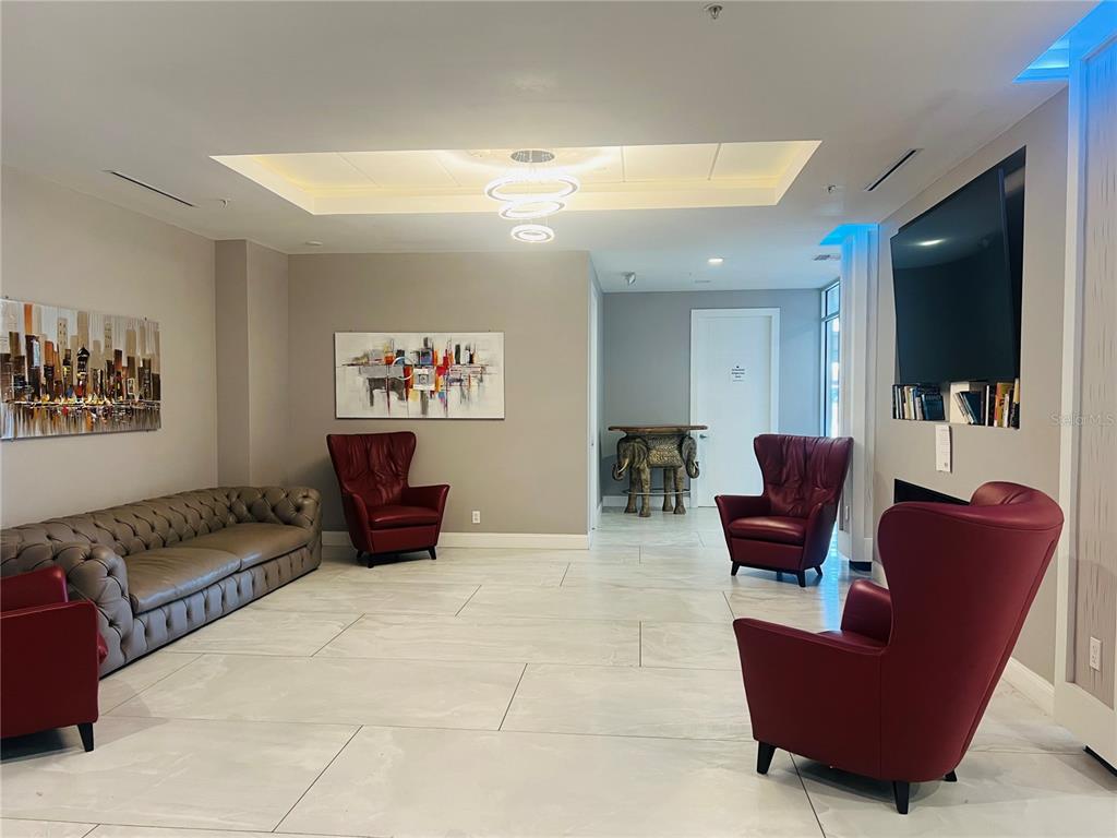 A modern lobby features a tufted sofa, red armchairs, tile flooring, and a tray ceiling — 1909 SOUTH ATLANTIC AVENUE UNIT 405/406, DAYTONA BEACH SHORES, FL
