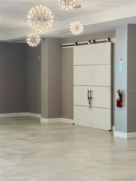 A room with light tile flooring, modern globe pendant lights, and a white sliding barn door — 1909 SOUTH ATLANTIC AVENUE UNIT 405/406, DAYTONA BEACH SHORES, FL