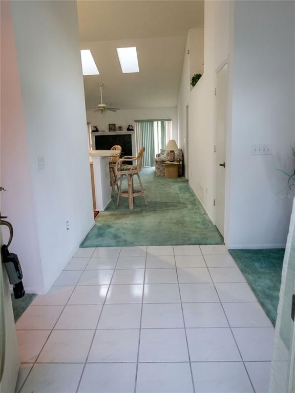 A tiled entryway leads into a living area with green carpeting and vaulted ceilings — 7369 HIGH LAKE DRIVE, ORLANDO, FL