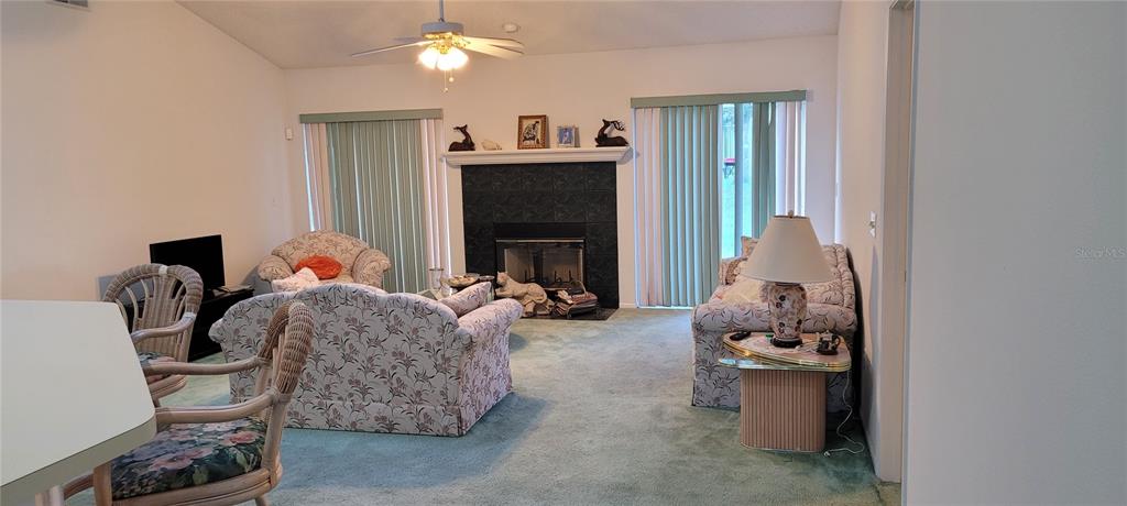 A living room features a black tiled fireplace, green carpeting, and two sliding glass doors — 7369 HIGH LAKE DRIVE, ORLANDO, FL