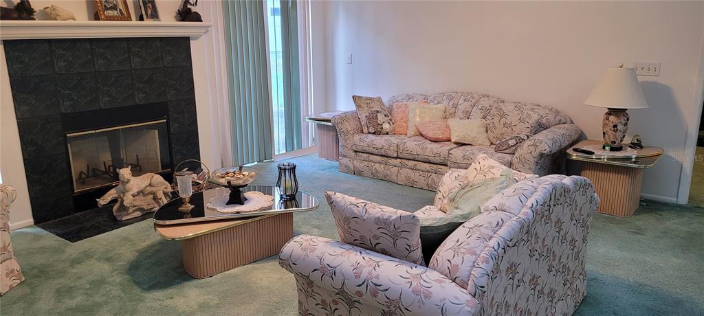 A living room features a fireplace, floral-patterned furniture, and light green carpeting — 7369 HIGH LAKE DRIVE, ORLANDO, FL