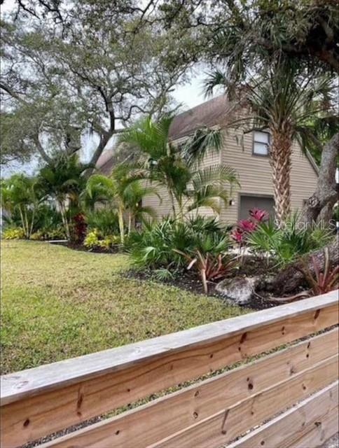 A tan house with a garage is partially obscured by palm trees and a wooden fence — 5311 CREEK DRIVE, SARASOTA, FL