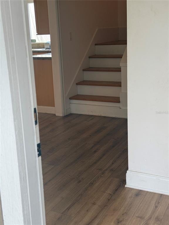 A view through a doorway shows wood-look flooring and a staircase with wooden treads — 5311 CREEK DRIVE, SARASOTA, FL