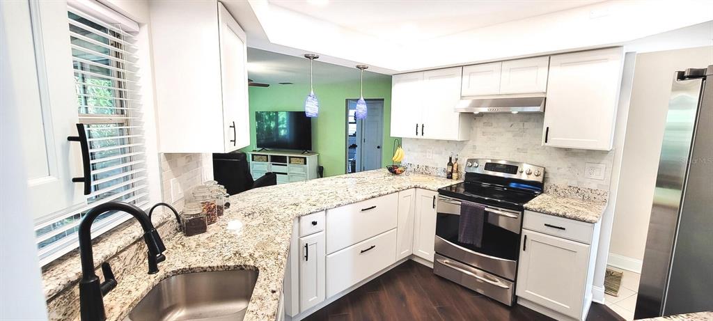 A kitchen features white cabinets, granite countertops, stainless steel appliances, and a black faucet — 755 KENT ROAD, VENICE, FL