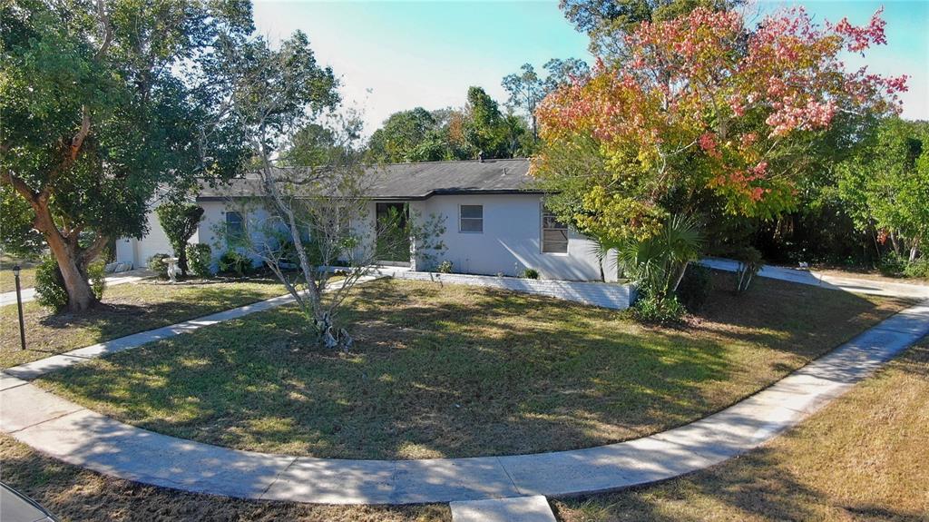 A single-story house with a light-colored exterior sits on a corner lot with mature trees — 1144 GERONA AVENUE, DELTONA, FL