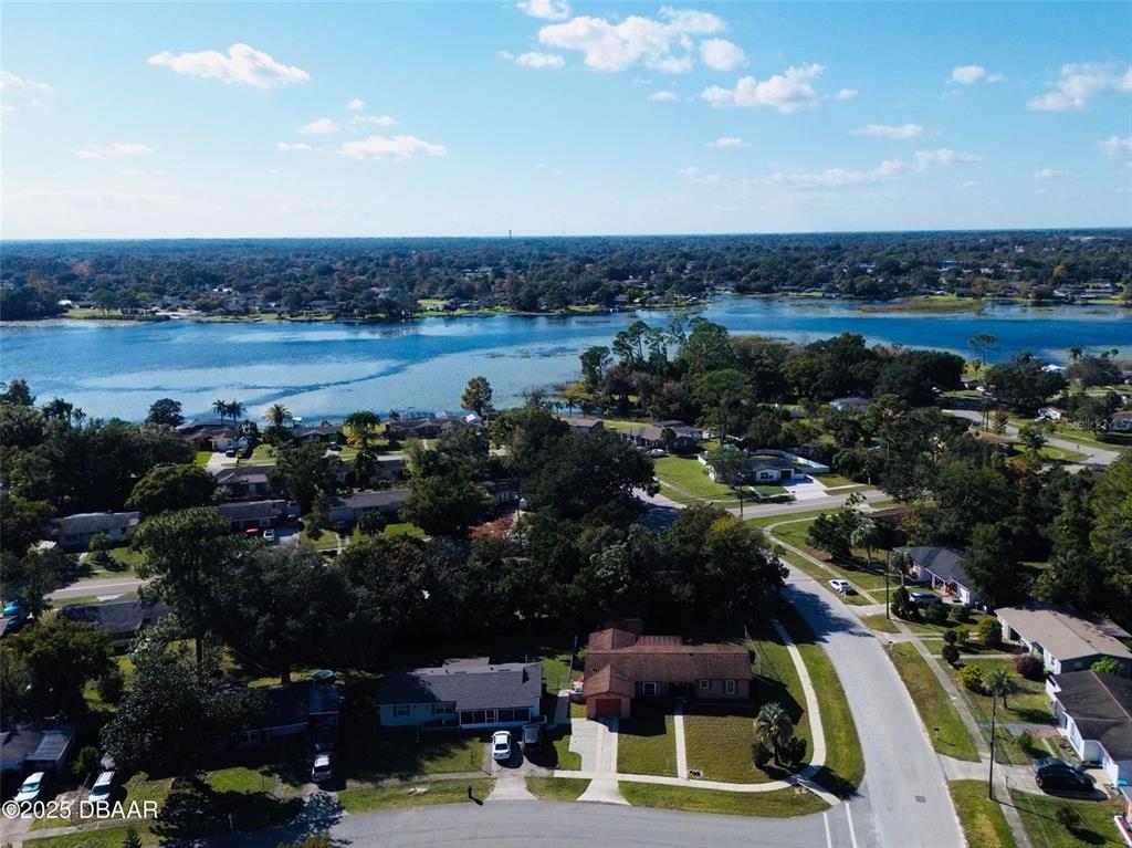 An aerial view shows a suburban neighborhood with houses situated near a large lake — 1144 GERONA AVENUE, DELTONA, FL
