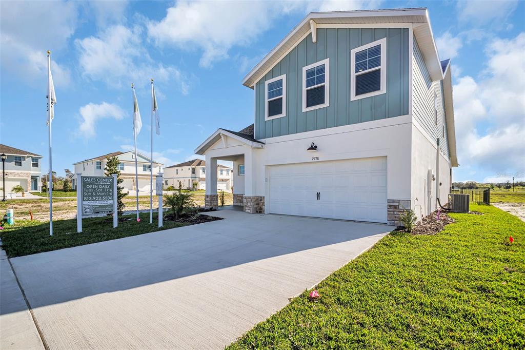 A two-story house with a white garage and blue siding stands under a cloudy sky — 7959 CHANDLER LAKE COURT, HUDSON, FL