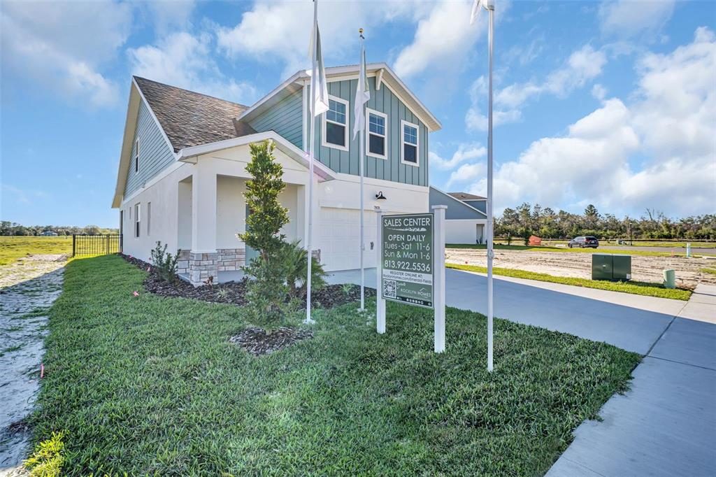 A two-story house with blue siding and a stone-accented entrance stands near a sales sign — 7959 CHANDLER LAKE COURT, HUDSON, FL