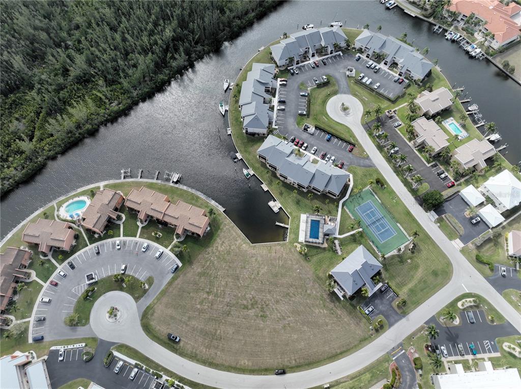 Aerial view of a waterfront residential complex featuring townhomes, a swimming pool, and tennis courts — 1341 ROCK DOVE COURT, PUNTA GORDA, FL