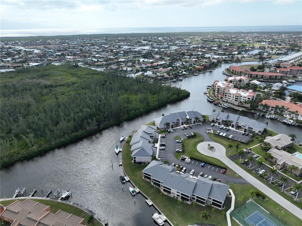 An aerial view shows multi-family residential buildings situated along a canal near a wooded area — 1341 ROCK DOVE COURT, PUNTA GORDA, FL