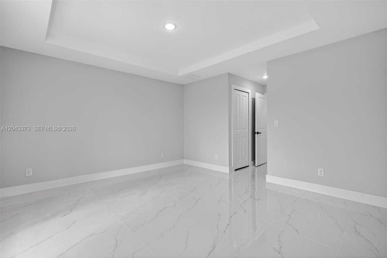 An empty room features light gray walls, white trim, and glossy white marble-patterned tile flooring — 1871 Tobin st, Lehigh Acres FL 33972, LEHIGH ACRES, FL