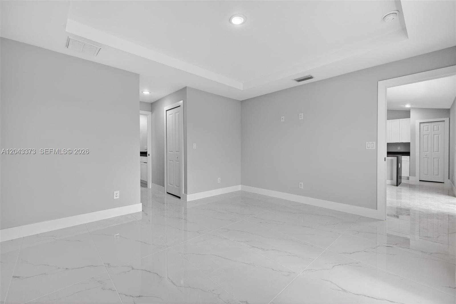 A bright, empty room features gray walls, white trim, and polished white marble-look tile flooring — 1871 Tobin st, Lehigh Acres FL 33972, LEHIGH ACRES, FL