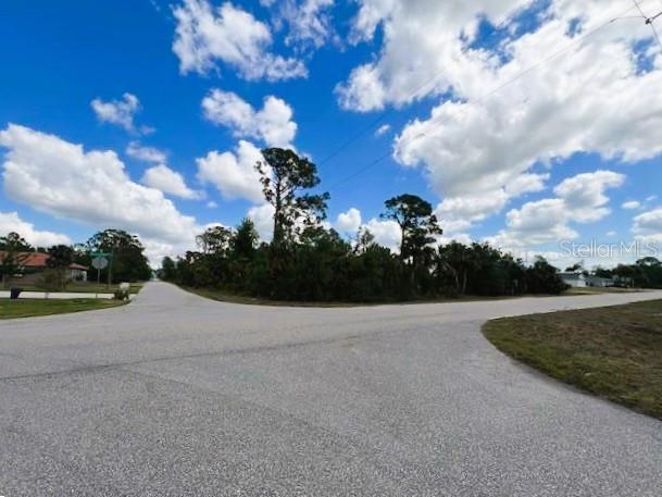 A corner lot with trees and vegetation sits at the intersection of two paved roads — 17128 WINTERGARDEN AVENUE, PORT CHARLOTTE, FL