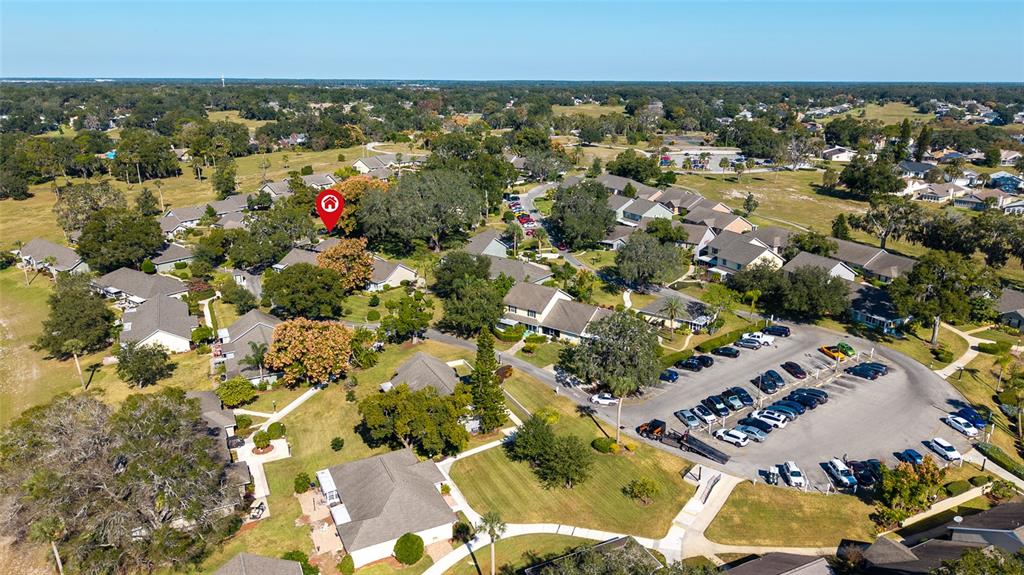 This aerial view shows a residential neighborhood with houses, green spaces, and a parking lot — 1329 VILLA LANE UNIT 45, APOPKA, FL