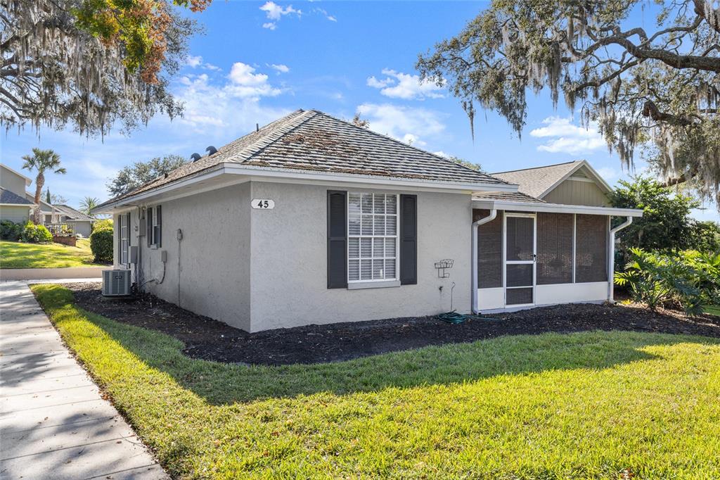 A single-story house with a screened-in porch, gray stucco walls, and a shingled roof — 1329 VILLA LANE UNIT 45, APOPKA, FL