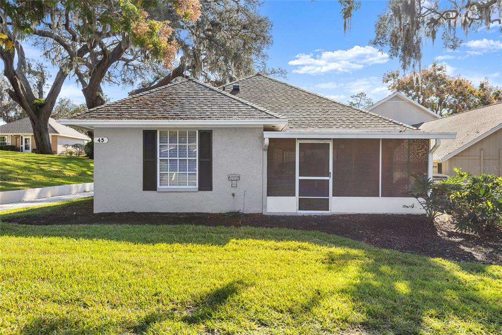 A single-story house with a gray stucco exterior, dark shutters, and a screened-in front porch — 1329 VILLA LANE UNIT 45, APOPKA, FL