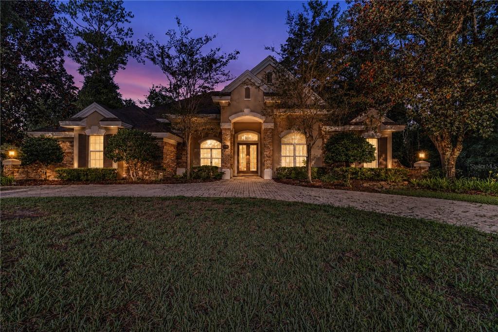 A single-story house with a stone facade and a paved driveway at twilight — 5038 SE 6TH AVENUE, OCALA, FL