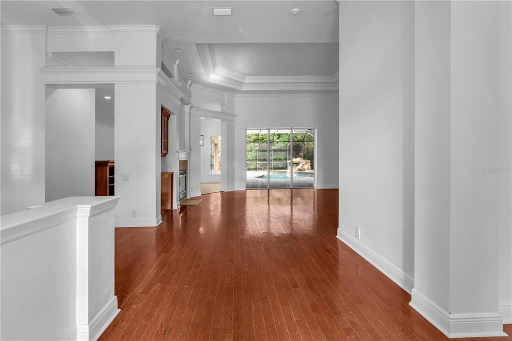 A spacious living room features hardwood floors, a tray ceiling, and sliding doors to a pool — 5038 SE 6TH AVENUE, OCALA, FL