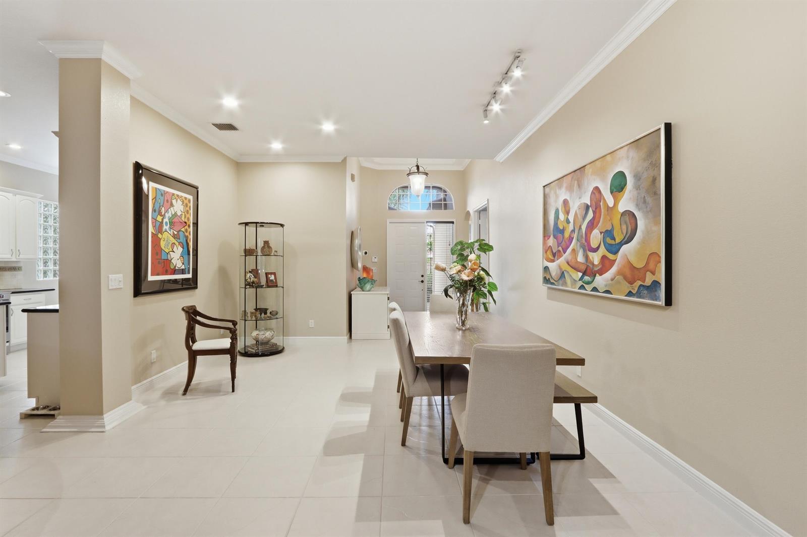 A kitchen with white cabinets, black countertops, stainless steel appliances, and a small wooden island — 5677 Via De La Plata Circle, Delray Beach FL 33484, DELRAY BEACH, FL