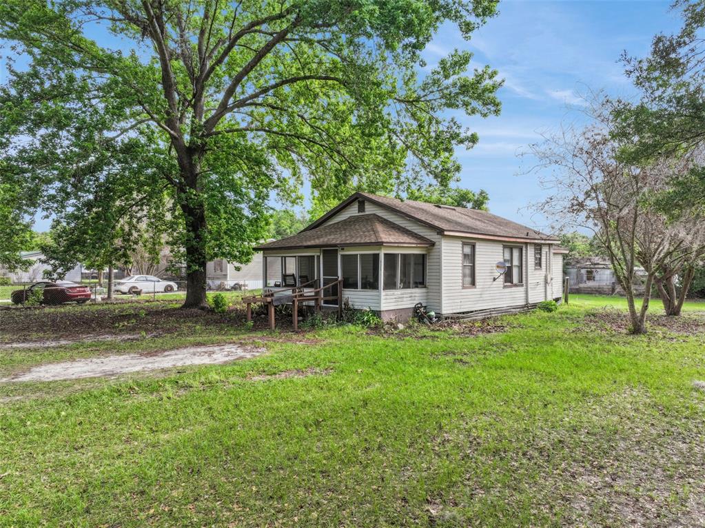A single-story house with light siding and a screened-in porch sits on a grassy lot — 4125 LAVON REYNOLDS LANE, LAKELAND, FL