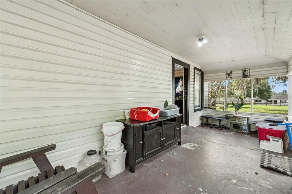 A covered porch with white siding, a black cabinet, and large windows overlooking a yard — 4125 LAVON REYNOLDS LANE, LAKELAND, FL