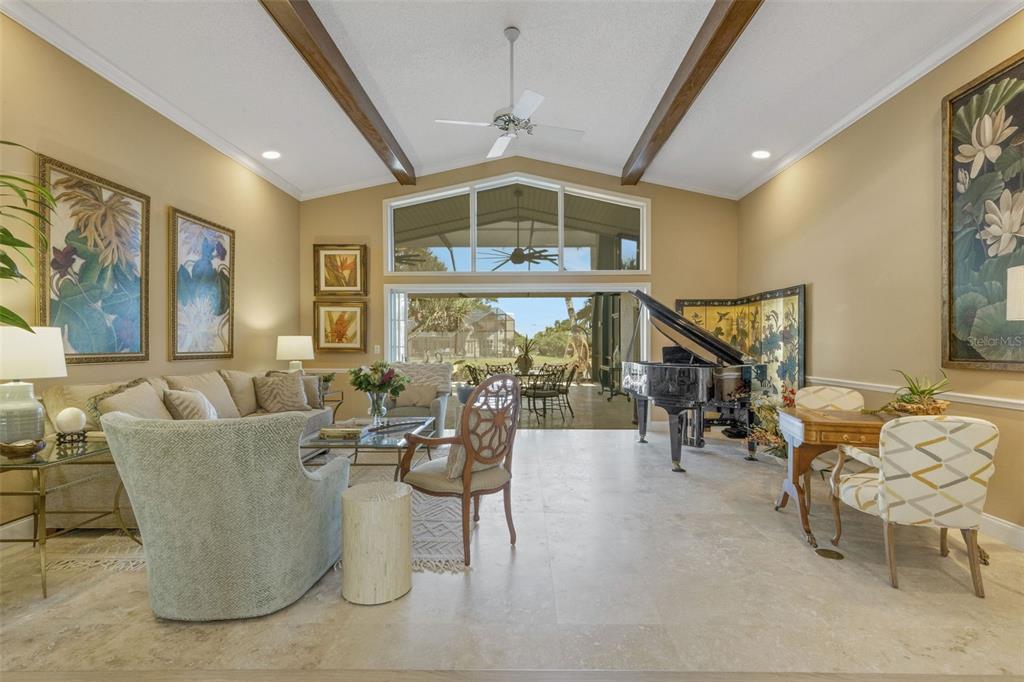 A spacious living room features a grand piano, vaulted ceilings, and large glass sliding doors — 5679 COUNTRY LAKES DRIVE UNIT 7, SARASOTA, FL