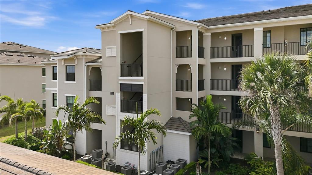 An exterior view of a multi-story apartment building with balconies and palm trees — 18008 GAWTHROP DRIVE UNIT 401, BRADENTON, FL