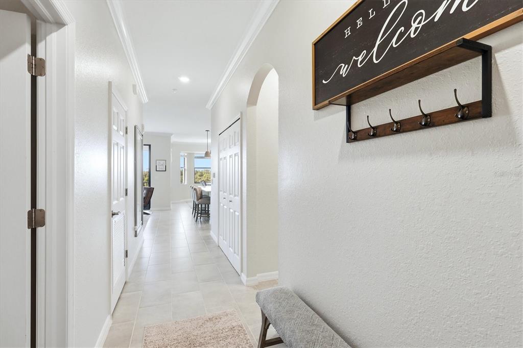A hallway with light tile flooring leads toward an open kitchen area — 18008 GAWTHROP DRIVE UNIT 401, BRADENTON, FL