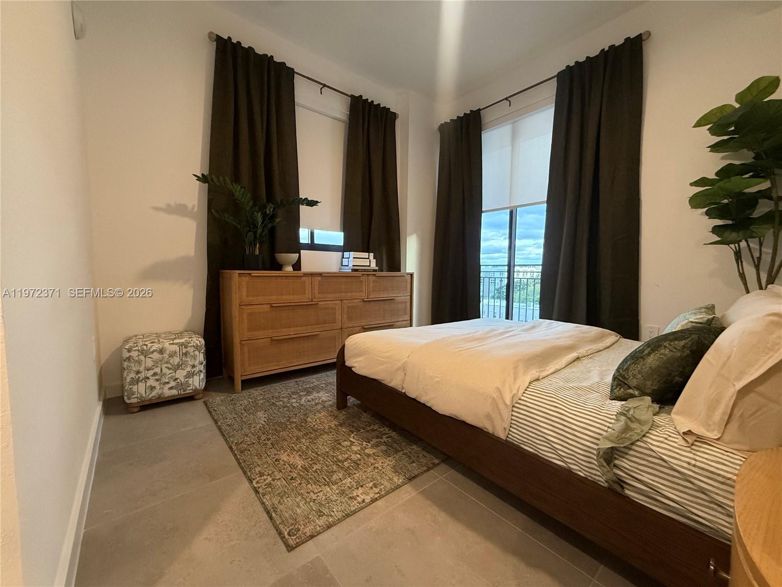 A bedroom features a wooden dresser, a bed with striped bedding, and dark curtains — 2001 Van Buren St # 545, Hollywood FL 33020, HOLLYWOOD, FL