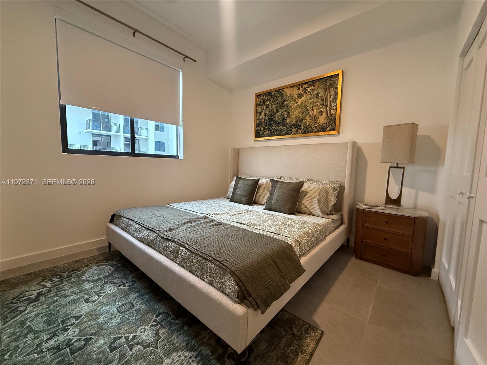 A bedroom features a beige upholstered bed, a wooden nightstand, and a patterned area rug — 2001 Van Buren St # 545, Hollywood FL 33020, HOLLYWOOD, FL