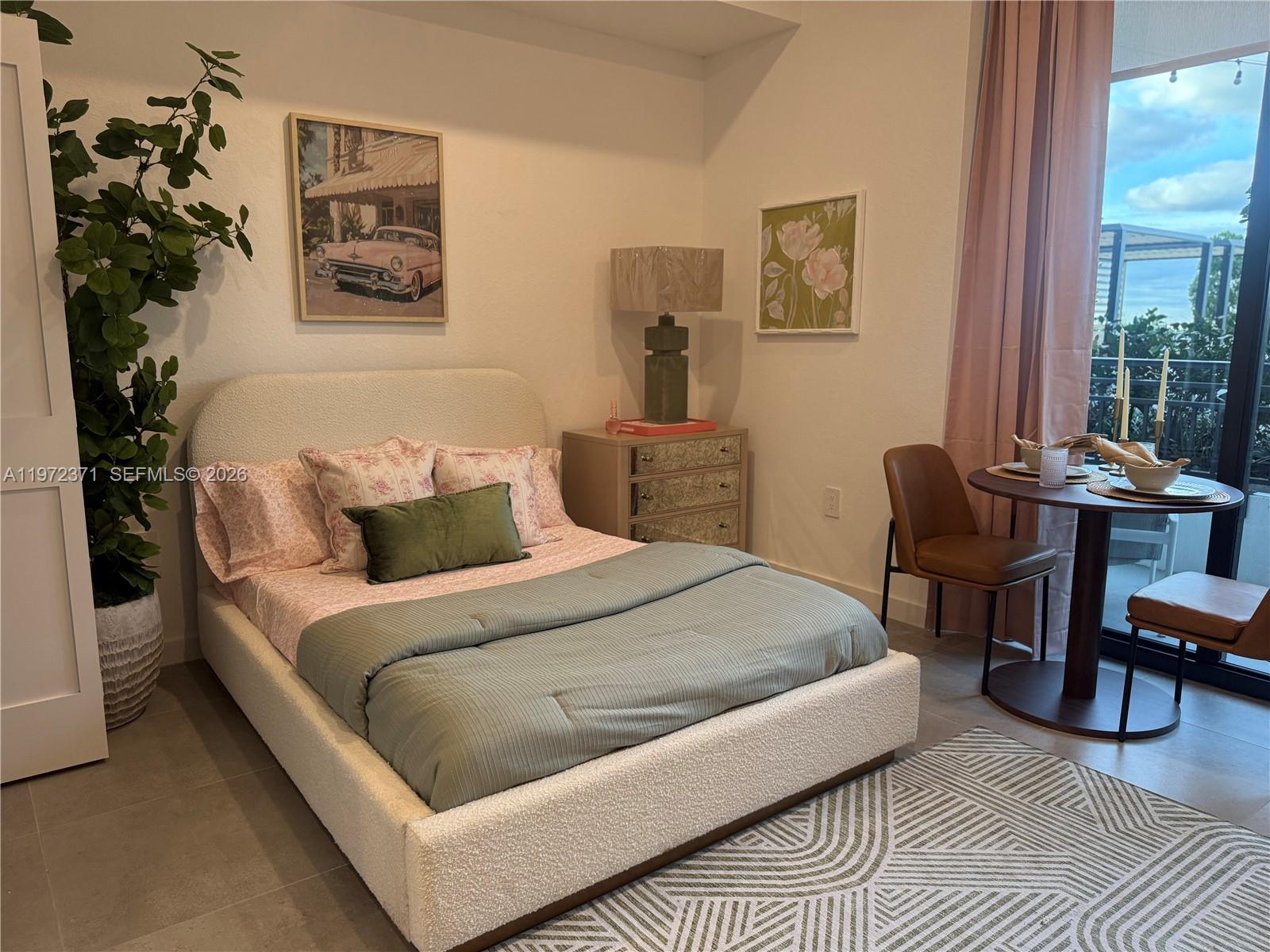 A bedroom features a white upholstered bed, a nightstand, a dining set, and a balcony — 2001 Van Buren St # 545, Hollywood FL 33020, HOLLYWOOD, FL