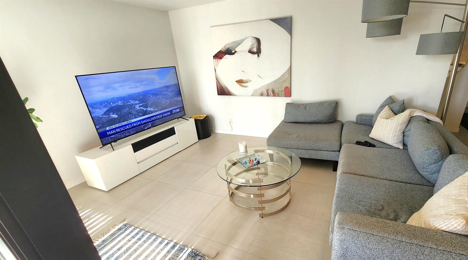 A living room features a gray sectional sofa, a glass coffee table, and a television — 2255 Lindell Boulevard # 4303, Delray Beach FL 33444, DELRAY BEACH, FL