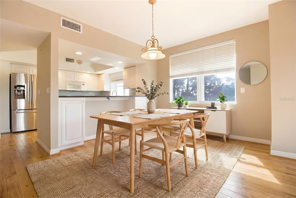 A dining area with a wooden table, chairs, and a rug sits before a kitchen — 1200 COUNTRY CLUB DRIVE UNIT 1101, LARGO, FL