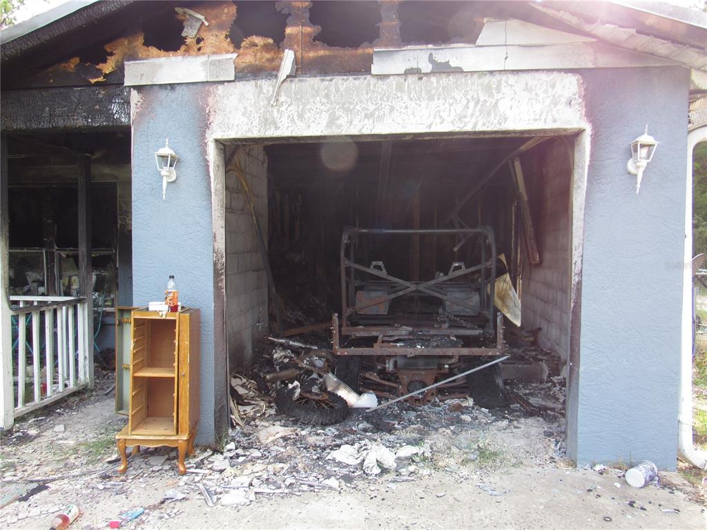A fire-damaged garage with a charred interior and a burnt vehicle frame inside — 5620 SW 181ST COURT, DUNNELLON, FL