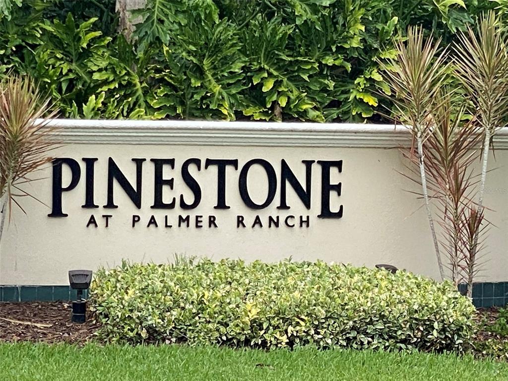 A beige stone monument sign displays the text Pinestone at Palmer Ranch — 8389 WINGATE DRIVE UNIT 2313B2, SARASOTA, FL