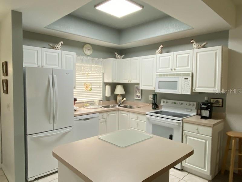 A kitchen with white cabinets, light countertops, a central island, and a recessed ceiling light — 8389 WINGATE DRIVE UNIT 2313B2, SARASOTA, FL