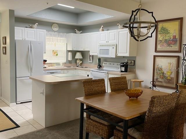 A kitchen with white cabinets, a center island, and a dining area with wicker chairs — 8389 WINGATE DRIVE UNIT 2313B2, SARASOTA, FL