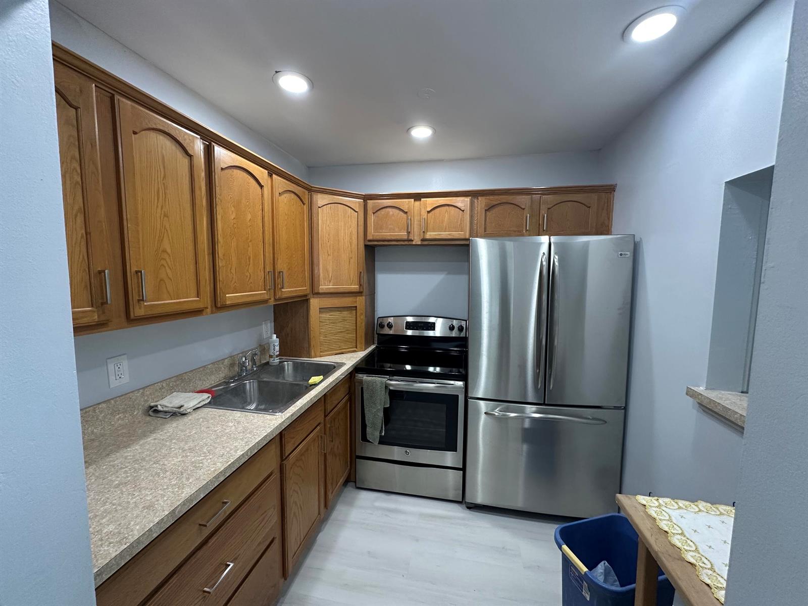 A kitchen features oak cabinets, stainless steel appliances, a double sink, and light-colored countertops — 21 Salisbury A, West Palm Beach FL 33417, WEST PALM BEACH, FL