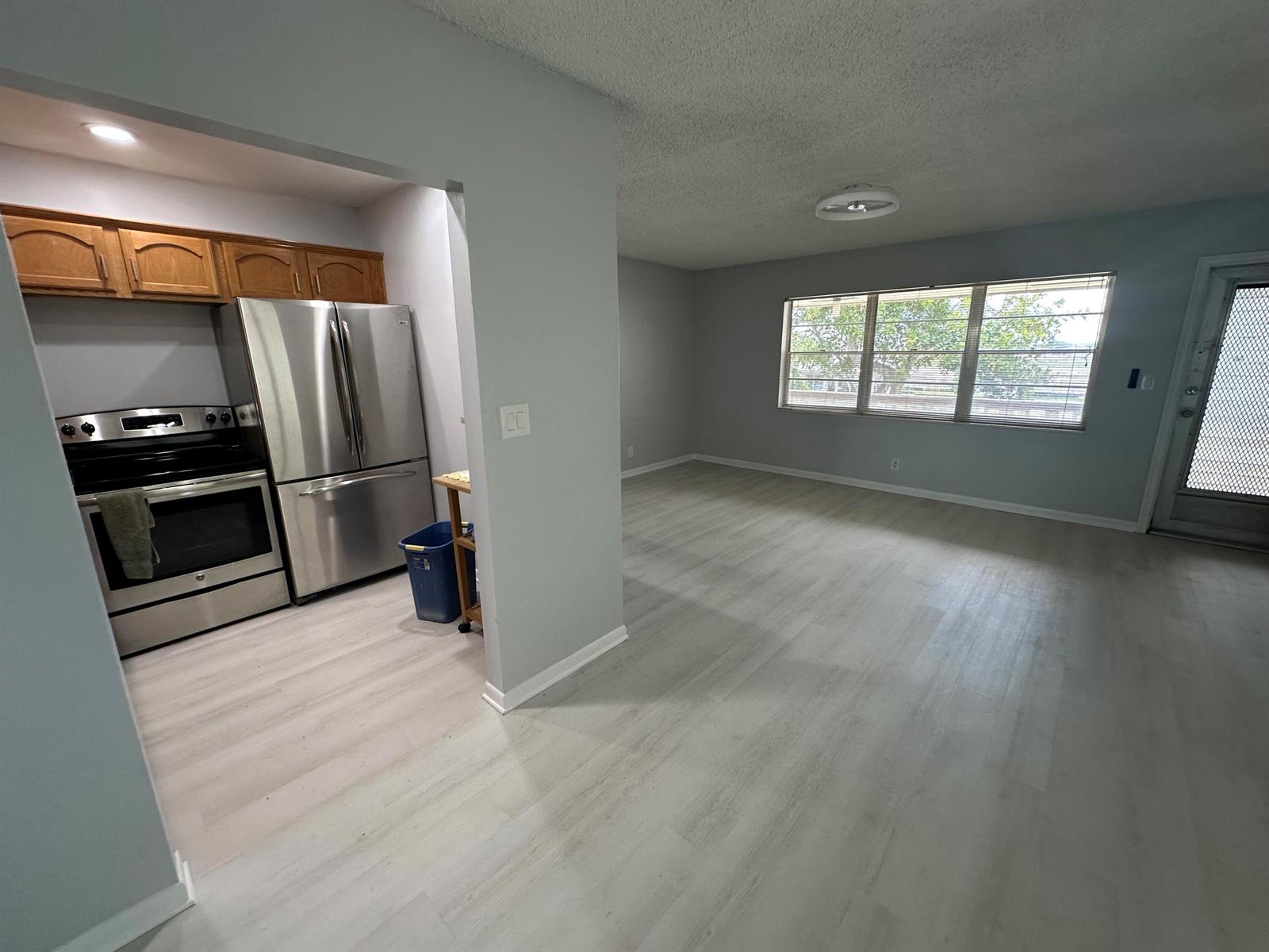 A kitchen with stainless steel appliances and wood cabinets opens into a spacious living area — 21 Salisbury A, West Palm Beach FL 33417, WEST PALM BEACH, FL