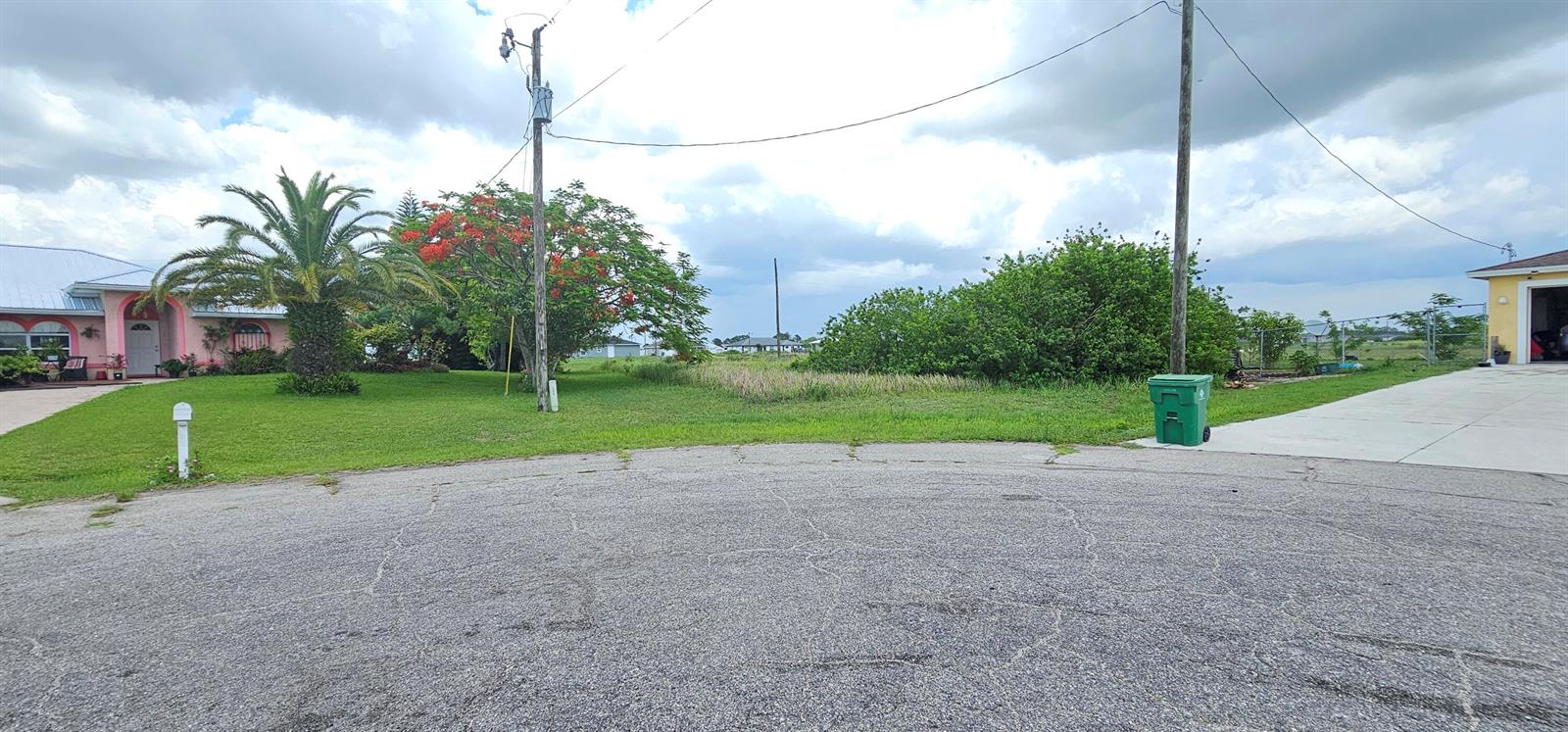 A vacant grassy lot sits between two residential houses under a cloudy sky — 9008 Abel Court, FL 33935, FL